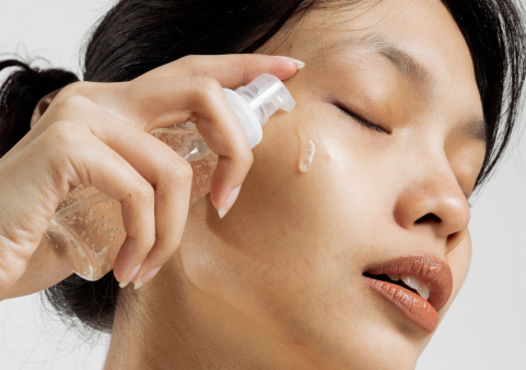 asian woman pputting on face spreay
